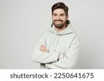 Young confident smiling happy cheerful unshaven caucasian man wear mint hoody look camera hold hands crossed folded isolated on plain solid white background studio portrait. People lifestyle concept