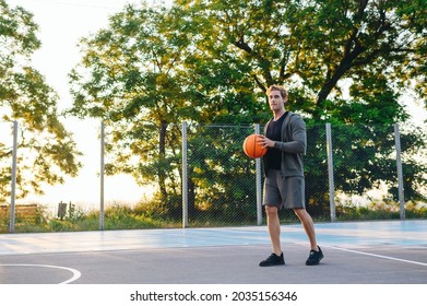 Young Confident Sporty Strong Caucasian Sportsman Man 20s Wearing Sports Clothes Training Shooting Free Throw Playing With Ball At Basketball Game Playground Court. Outdoor Courtyard Sport Concept.