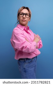 young confident stylish blond businesswoman in glasses is dressed in a pink shirt and jeans - Shutterstock ID 2311782821