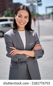 Young confident successful smiling Asian business woman, professional entrepreneur, real estate agent wearing suit and earphones standing on city street with arms crossed. Vertical portrait. - Shutterstock ID 2181776753