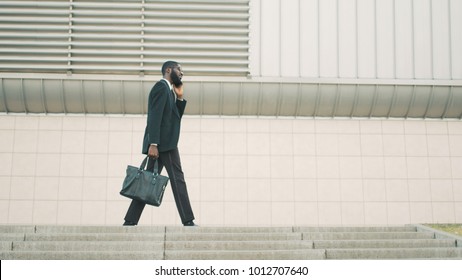 Young Confidentd African American Business Man Talking On The Cell Phone While Walking On The Stairs, Steps Near Office Center Building.