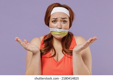 Young Confused Sad Chubby Overweight Plus Size Big Fat Fit Woman In Red Top Gagged With Measuring Tape Warm Up Training Isolated On Purple Color Background Gym Home Workout Motivation Sport Concept.