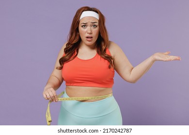 Young confused sad indignant chubby overweight plus size big fat fit woman in top hold measure tape waist spread hand warm up train isolated on purple color background home gym Workout sport concept.