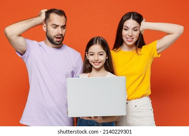 Young Confused Sad Parents Mom Dad With Child Kid Daughter Teen Girl In Basic T-shirts Hold Laptop Pc Computer Isolated On Yellow Background Studio Portrait. Family Day Parenthood Childhood Concept.