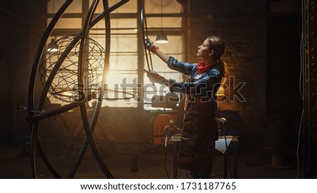 Young Contemporary Female Artist Dressed as a Tomboy is Fitting a Metal Ring to a Tube Sculpture in a Studio Workshop. Empowering Woman Makes Modern Brutal Abstract Artwork Out Of Steel.