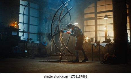 Young Contemporary Female Artist is Grinding Her Metal Tube Sculpture with a Handheld Power Tool in a Studio Workshop. Empowering Woman Makes Modern Brutal Abstract Artwork Out Of Metal.