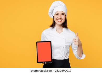 Young cook baker woman wear white shirt black apron uniform toque chef hat hold use blank screen digital tablet pc computer look for recipe isolated on plain yellow background. Cooking food concept - Powered by Shutterstock