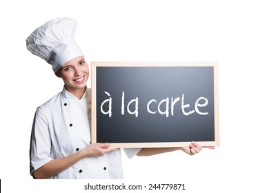 young cook presenting a blackboard with the message "Ã?Â  la carte"