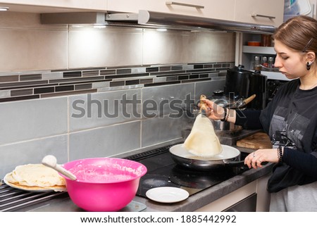 The young cook turns the pancake in the pan to the other side using the kitchen spatula. Homemade pancakes.