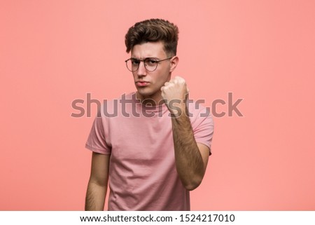Young cool caucasian man showing fist to camera, aggressive facial expression.