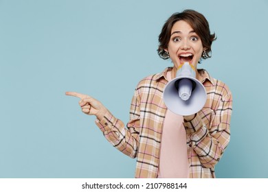 Young cool happy woman 20s in brown shirt hold scream in megaphone announces discounts sale Hurry up point index finger aside on workspace isolated on pastel plain light blue color background studio
