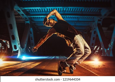 Young cool man break dancer on urban bridge with cool and warm lights background. Tattoo on body. - Shutterstock ID 1219644334