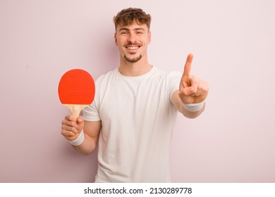 young cool man smiling and looking friendly, showing number one. pingpong concept