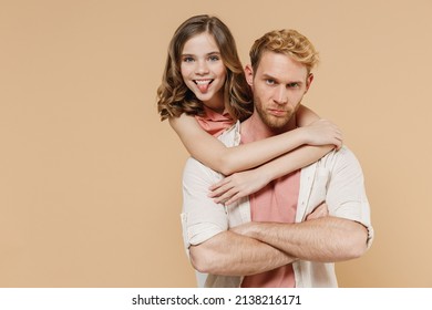 Young Cool Parent Man Have Fun With Child Teen Girl In Casual Pastel Clothes Dad Little Kid Daughter Hug Stand Behind Kidding Show Tongue Isolated On Beige Background Father's Day Love Family Concept.