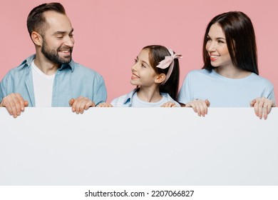 Young Cool Parents Mom Dad With Child Kid Daughter Teen Girl In Blue Clothes Hold Empty Billboard For Promotional Content, Place Area For Text Or Image Isolated On Plain Pastel Light Pink Background