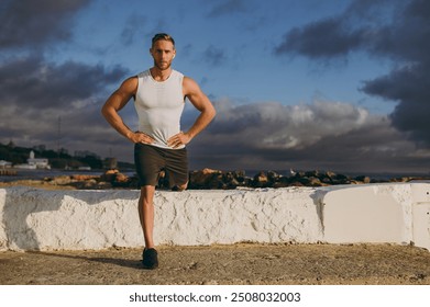 Young cool strong sporty athletic fit sportsman man he wears sports clothes earphones do squats stretch leg warm up training at sunrise sun dawn over sea beach outdoor on seaside in summer day morning - Powered by Shutterstock