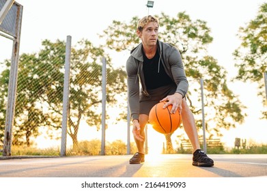 Young cool sunlit concentrated sporty sportsman man wear sports clothes doing handling drills training holding in hand ball play at basketball game playground court Outdoor courtyard sport concept. - Powered by Shutterstock