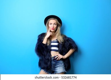 Young Cool Woman In Fur And Hat On Blue Background