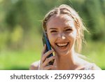 A young country girl enjoys a sunny summer day on her family farm, talking on her cellphone. Amid lush green fields and tall trees, she smiles, showing emotion in her call, feeling free in the warm br