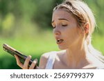 A young country girl enjoys a sunny summer day on her family farm, talking on her cellphone. Amid lush green fields and tall trees, she smiles, showing emotion in her call, feeling free in the warm br