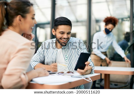 Young coupe enjoying while using mobile phone at reopened cafe during coronavirus pandemic.
