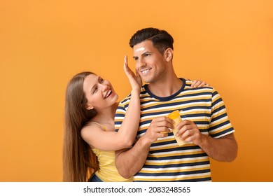 Young couple applying sunscreen cream against color background - Powered by Shutterstock