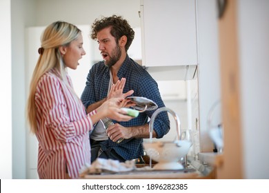 A Young Couple Arguing About Housework In A Tense Atmosphere At The Kitchen. Kitchen, Housework, Home, Relationship