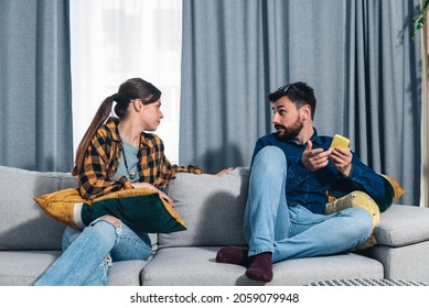 Young couple arguing about text messages on the boyfriends phone where girlfriend is jealous for finding the communication with other woman on boyfriends smartphone. Couple social network concept