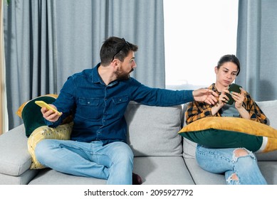 Young couple arguing about text messages on the boyfriends phone where girlfriend is jealous for finding the communication with other woman on boyfriends smartphone. Couple social network concept