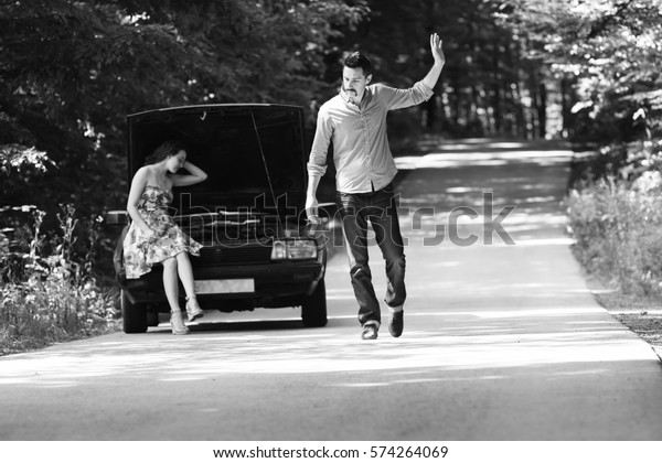 Young couple arguing with the defective\
car,black and white\
photography