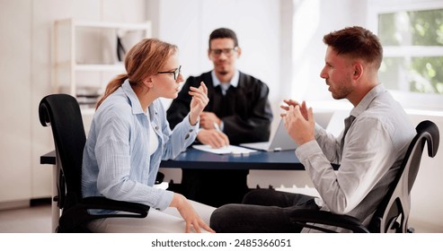 Young couple arguing in front of male judge, contemplating divorce. Family lawyer deals with their dispute, hoping for resolution. - Powered by Shutterstock