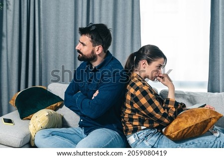 Young couple are arguing on the couch in their home and having difficulty and problems in a relationship and marriage sitting back to back ignoring and not talking to each other, relationship problems