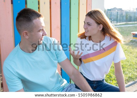 Young couple arguing outdoors. Redhead girl is angry at her boyfriend.