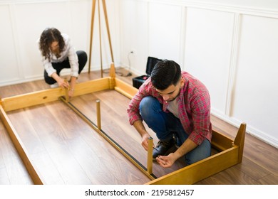 Young Couple Assembling A New Bed Frame Together And Using Tools While Renovating Their Bedroom