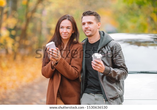 Young couple in\
autumn with coffee\
outdoors