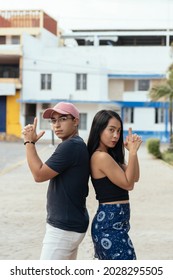 Young Couple Back To Back Making A Handgun Gesture