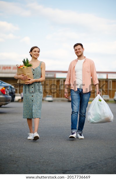 Young couple with\
bags on supermarket\
parking