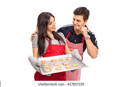 Young couple baking and eating cookies together isolated on white background