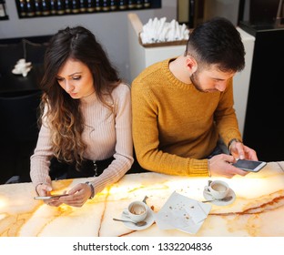 Young couple at the bar while using mobile phone. Social networks in real life can have negative effects.