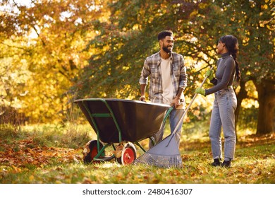 Young Couple With Barrow Raking Leaves In Autumn Garden At Home Together - Powered by Shutterstock