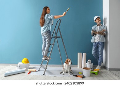 Young couple with Beagle dog doing repair near blue wall in their new house - Powered by Shutterstock