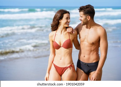 Young Couple Of Beautiful Athletic Bodies Walking Together On The Beach Enjoying Their Holiday At Sea