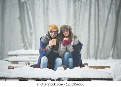 Young Couple With Blanket Drinking Coffee And Smiling Outdoors In Snow 