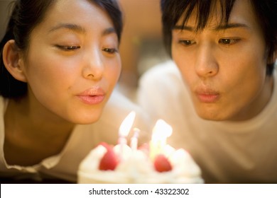 A young couple blowing off birthday candle