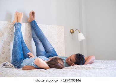 Young couple boy and girl lay down on bed in the bedroom at home or hotel - love and relationship happy couple together in the morning - real lifestyle modern people interracial