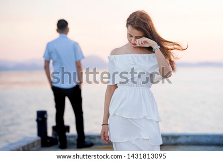 Young couple break up at the sea deck. Girl crying and walk away from man in concept love hurts,hard relationship,sad love story,when love is ended. Broken heart syndrome. How to fix a broken heart.