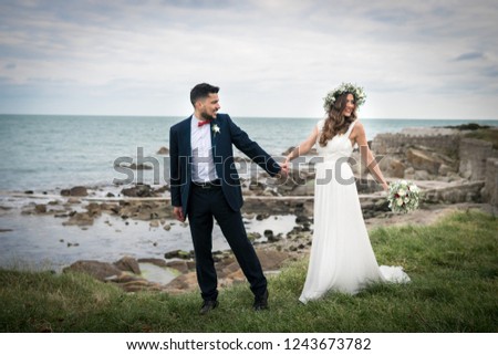 young couple bride groom getting married wedding posed photos at seaside sea beach hairpiece flowers bouquet 