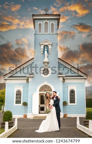 young couple bride groom getting married wedding posed photos at blue christian church hairpiece flowers bouquet 