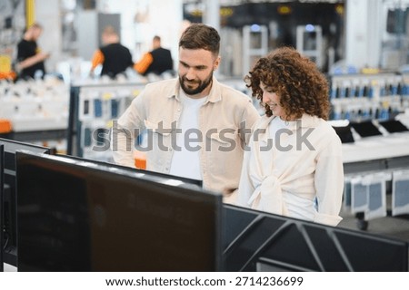 Young couple browsing in a consumer electronics store, comparing options while considering the latest televisions for their home entertainment setup
