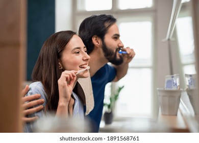 Young couple brushing teeth in front of mirror indoors at home. - Powered by Shutterstock